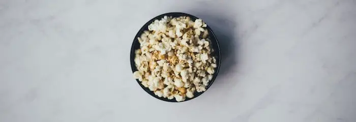 A blue bowl of popcorn, placed on a table.