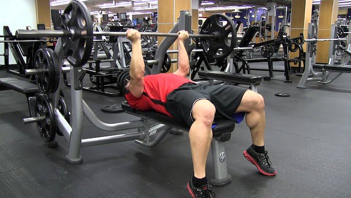 Man in the gym doing a reverse grip press.