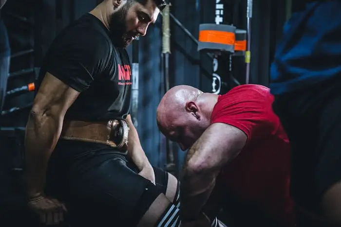 Two men in the gym, one wearing a lifting belt.