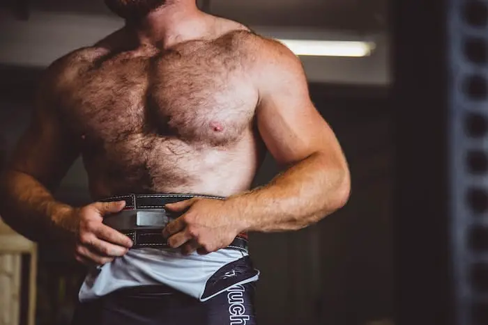 Shirtless man in the gym, wearing a weightlifting belt.