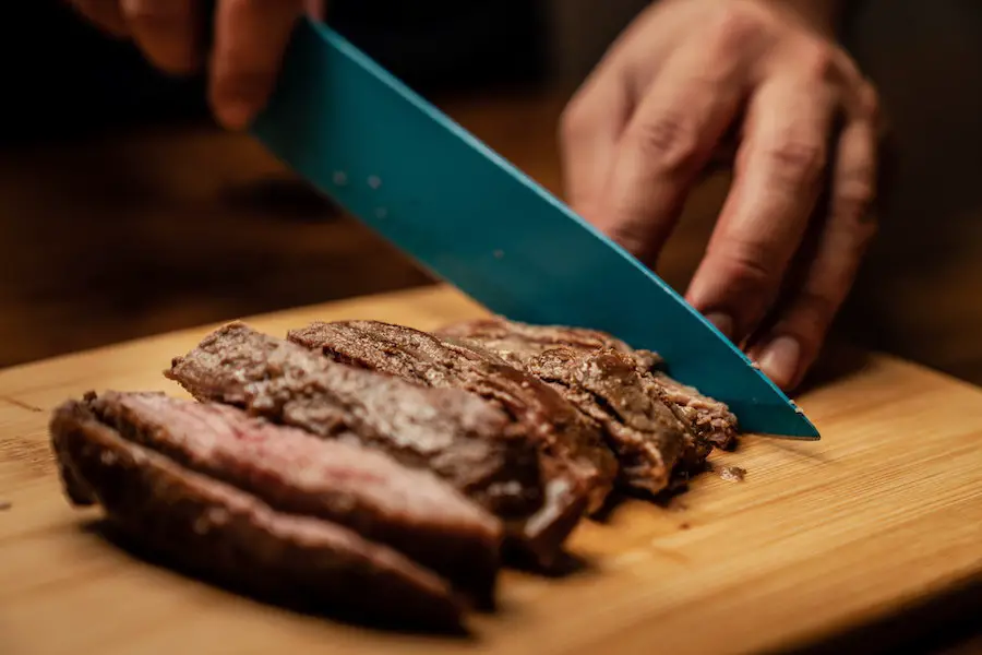 Man cutting steak on a cutting board.