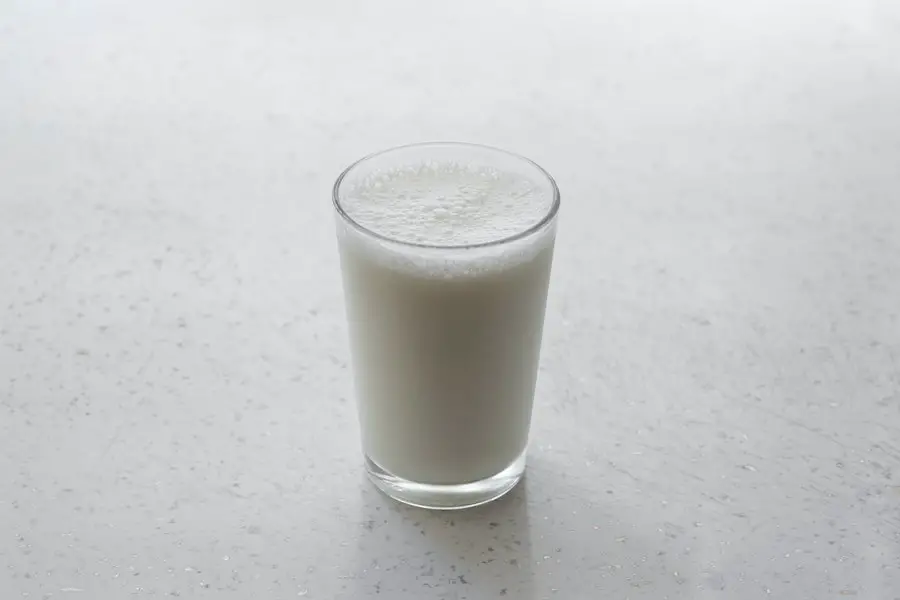 Glass of milk sitting on a counter.